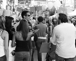 VAGUE PROTEST : Ryan Miller, a participant in New Arts Collective’s vague protest flash mob argues his points of protest with a curious passerby. - PHOTO BY STEVE E. MILLER