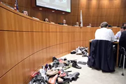 SHOES OF SHAME: They didn’t throw them, but audience members left a pile of shoes to show county supervisors how they felt about the Santa Margarita Ranch project. - PHOTO BY STEVE E. MILLERPHOTO BY STEVE E. MILLER