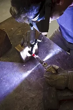 Alan Baxter welds the base of the bronze to the microphone figurine. - PHOTO BY STEVE E. MILLER