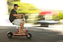 ELECTRIC PERSONALITY : San Luis Rides owner, Jake Carter, buzzes past traffic on an electric Go-Ped Scooter. - PHOTO BY STEVE E MILLER