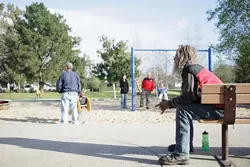 Mike sits on a bench at Meadow Park while families play with their children in the sand box. Seemingly none of the families were afraid nor did they protest against the handful of men and women hanging around the space. - PHOTO BY STEVE E. MILLER