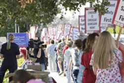 LINE OF SIGNS : On July 26, members of the California Nurses Association and other supporters marched with signs and shouted slogans to call awareness to ongoing negotiations with Catholic Healthcare West. - PHOTO BY STEVE E. MILLER
