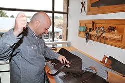 HANDMADE:  Ty Smith hand cuts and sews every leather item, like wallets and messenger bags, sold at Hide and Tallow in Cambria. - PHOTO BY DYLAN HONEA-BAUMANN