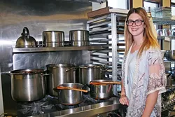 SLURP TO YOUR HEALTH: The Wellness Kitchen doesn’t just smell good. Its volunteers do good every day when they create life-affirming, nutrient-dense bone broth. Volunteer and health coach Ashley Beels checks on the latest batch of rebuilding beef bone broth. - PHOTO BY HAYLEY THOMAS