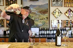 WINE NOT?: Michael Rice, sales manager for Harmony Cellars—the winery known for its chardonnay (on the right) just up the road from the town—pours wine at the tasting room. - PHOTO BY DYLAN HONEA-BAUMANN