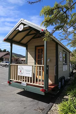 COMMUNITY VILLAGE: This tiny home on wheels is a mock-up of the structures that Hope’s Village wants to someday build into a facility to help homeless people/families transition into a more permanent housing situation. - PHOTO BY DYLAN HONEA-BAUMANN