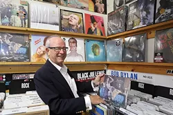 TAKES ME BACK: Glen Blosser flips through old David Bowie records at Boo Boo Records in San Luis Obispo, where his photos of the legendary glam rocker are currently up on display. - PHOTO BY DYLAN HONEA-BAUMANN