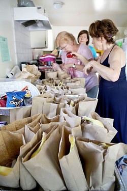 PEOPLE&rsquo;S KITCHEN:  Volunteers Debbie, Clara, and Mary (left to right) prepare paper bag dinners at Second Baptist Church in Paso Robles for locals in need. The People&rsquo;s Kitchen is able to serve dinners Monday through Friday because of the efforts of faith-based organizations. - PHOTO BY DYLAN HONEA-BAUMANN