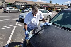 SPRAY ON, WIPE OFF: Lamar Harrison from Clean and Green Auto Care “washes” a car in the Smart & Final parking lot off Grande Avenue in Arroyo Grande without using any water. - PHOTO BY CAMILLIA LANHAM