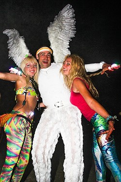 FESTIVAL FASHION:  Festival fan Samy Boogaard (left) meets and embraces a man dressed as an angel, along with another happy-go-lucky young lady on the dance floor in 2014. - PHOTO BY DYLAN HONEA-BAUMANN