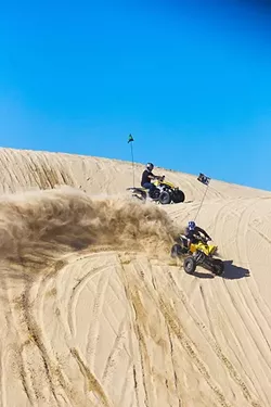 POUNDING SAND: ATV riders drive around on one of the hills in the Oceano Dunes State Vehicular Recreation Area on Jan. 28. Dust carried by the wind up to the Arroyo Grande/Nipomo Mesa is one of the issues that has plagued the state park. - PHOTO BY JAYSON MELLOM
