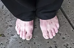 GETTING DRY : After a day of pouring rain, one man holds onto his wet shoes while waiting in line for the 5 Cities Homeless Coalition’s emergency shelter on Feb. 17. - PHOTO BY JAYSON MELLOM