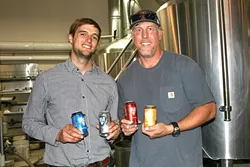 WE CAN DO IT: From left, SLO Brew Director of Marketing Brian Kerr and Brewmaster Steve Courier showcase their new 23-ounce cans. - PHOTO BY HAYLEY THOMAS