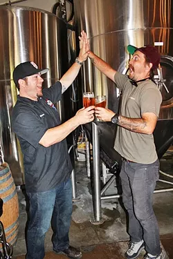 BEER FIVE: Central Coast Brewing Co. Head Brewer Brendan Gough (left) and Libertine Brewing Co. Co-Owner/Brewmaster Tyler Clark go for a “high-five/beer-five.” - PHOTO BY HAYLEY THOMAS