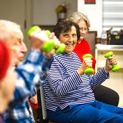 MOVING TOGETHER: Attendees of the SLO Senior Citizens Center’s chair exercise program get to sit, stretch, and exercise in a group. Socializing, singing, and laughter are all part of the program as well. - PHOTO BY JAYSON MELLOM