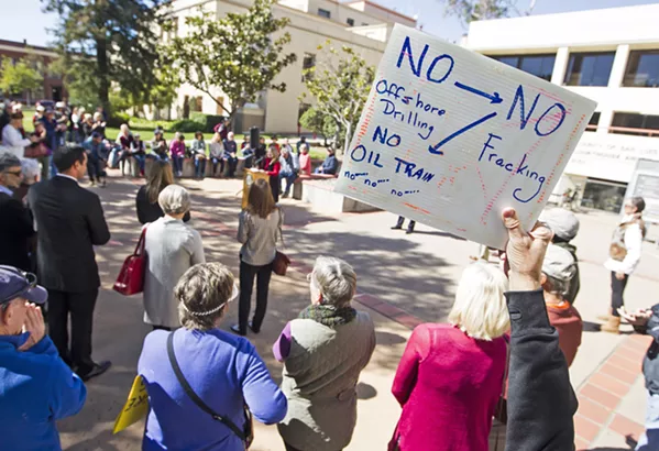 SIGN OF THE TIMES An activist holds up a sing at a recent anti-oil drilling press conference detailing what he believes to be the current fight in SLO County: the Phillips 66 rail spur, a petition to ban fracking, and resistance to offshore oil drilling. - PHOTO BY JAYSON MELLOM