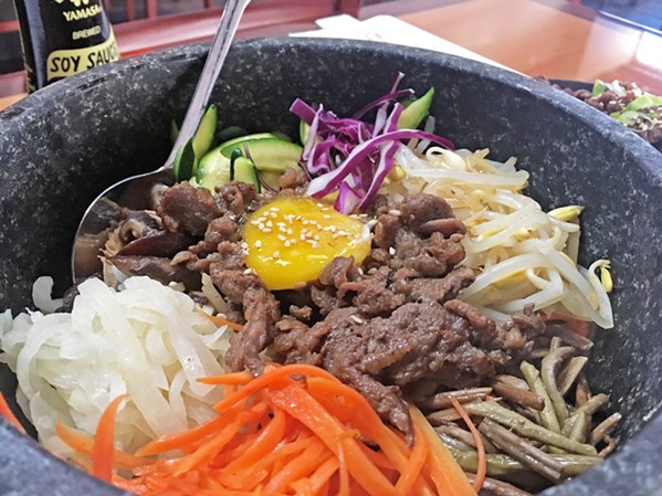 THAT SAUCE THOUGH Asian Bistro's Hot Stone Bibimbap sizzles for several minutes after it gets to the table. It comes with delicious house-fermented, spicy-sweet sauce to drizzle all over the bowl as you mix that egg yolk in with rice, beef, and fresh veggies. - PHOTO BY CAMILLIA LANHAM
