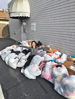 PILES OF CLOTHES Asia Croson, founder of the Clothing Swap and Drive, sits among bags of clothes left over after one day-long swap event. The event's remaining garments are donated to Stand Strong and other charities. - PHOTO COURTESY OF ASIA CROSON