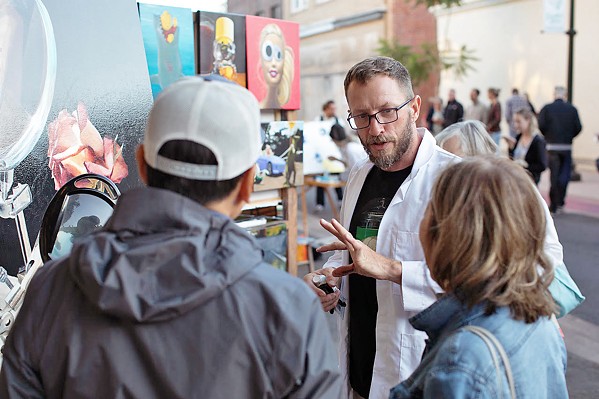NEW ACCESS POINTS Artist and member of Lamp Light Arts Joshua Talbott speaks with folks at the SLO Farmers' Market whose attention was grabbed by the live painters on Garden Street. - PHOTO COURTESY OF IVAN DITSCHEINER