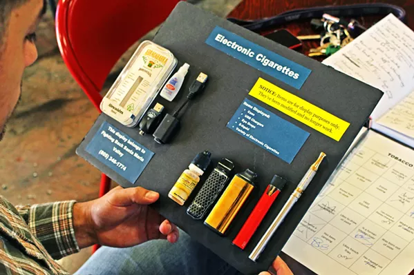 ELECTRONIC NICOTINE A community member holds a poster displaying vape pens, e-cigarettes, and e-juices that were confiscated from students at high schools in the Santa Maria Valley. - FILE PHOTO BY KASEY BUBNASH