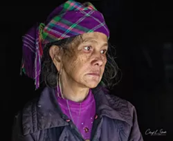 A WOMAN WITH A STORY Cheryl Strahl's Thoughtful in Hau Thao is a portrait featuring a dark, monochromatic background. The woman seen in the picture was caring for both her daughter and her grandson at the time the photo was taken. - PHOTO COURTESY OF CHERYL STRAHL