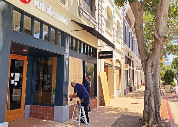 BOARDING UP Workers drill boards over Lululemon's windows in downtown San Luis Obispo as businesses braced for a protest on June 3. - PHOTO BY CAMILLIA LANHAM