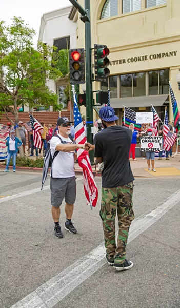 RECONCILING A Black Lives Matter protester fist bumps with a counterprotester on Aug. 25 after discussing why they believe what they do about the movement. - PHOTO BY JAYSON MELLOM