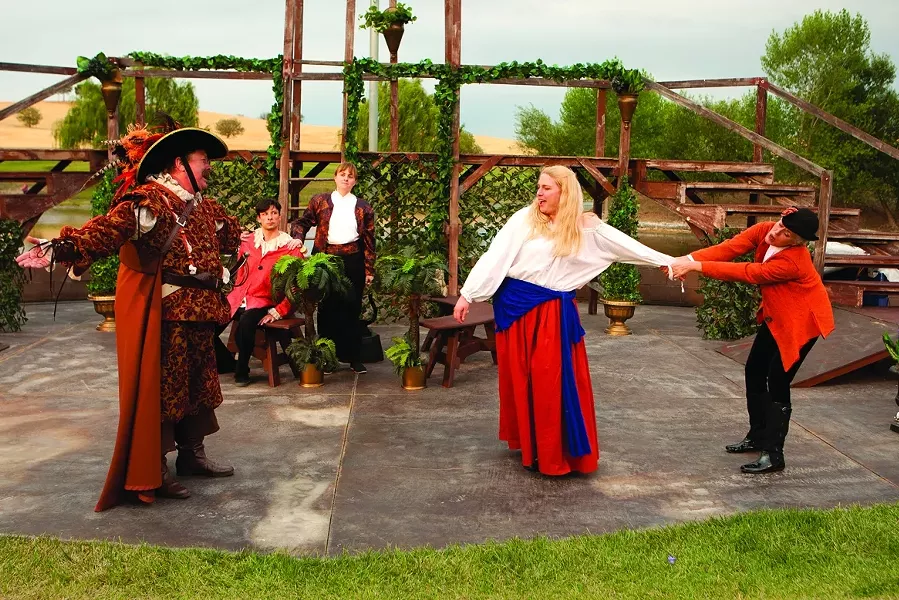 THE CLOWN AND THE COUNTRY WENCH: The pompous Spanish knight Don Armado (David Hance, left) captures the country wench Jacquenetta (Krystal Kirk, being dragged) whom he loves, as a punishment for the clown Costard (Sean Peters, seated in the background), whom she loves. - PHOTO BY STEVE E. MILLER