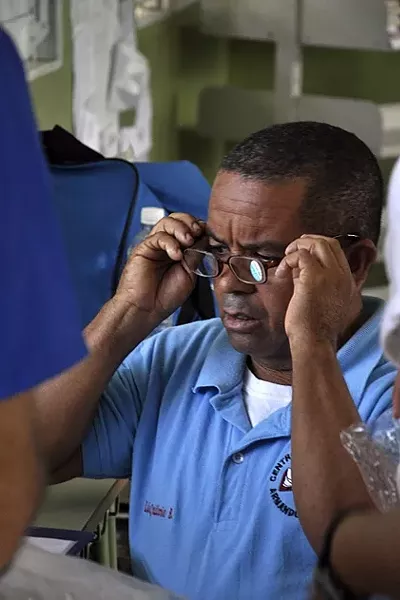 GIFT OF SIGHT: A patient tries on a pair of glasses to see if they’ll make it easier for him to read. On the November trip, Waves of Health paired more than 100 reading glasses with people who needed them. - PHOTO BY CAMILLIA LANHAM