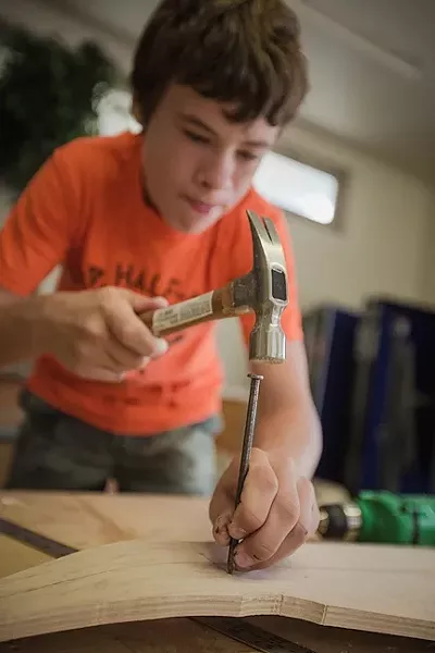 GRINDING FOR GRADES: Quinn Brussel hammers a nail into his D.I.Y. skateboard. - PHOTO BY KAORI FUNAHASHI
