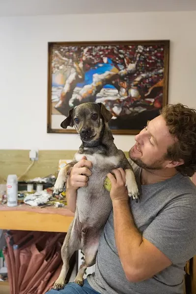MAN’S BEST FRIEND: Jordan Quintero hangs out with his dog, Beckman, at his studio in Arroyo Grande. Note: Quintero is the one on the right. - PHOTO BY KAORI FUNAHASHI