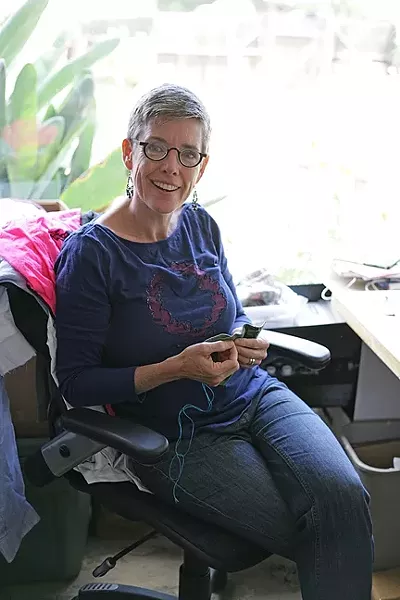 CREATOR: Ragtime member Liz Rhoads Cordoba, wearing one of her “Alabama Chanin” creations, sits at her well-lit sewing station. - PHOTO BY GLEN STARKEY