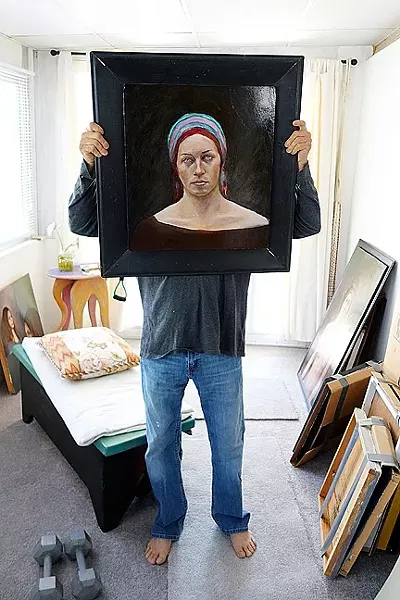 THE ARTIST AND A PORTRAIT : David Settino Scott holds one of the female portraits he’ll display through July in Steynberg Gallery. - PHOTO BY GLEN STARKEY