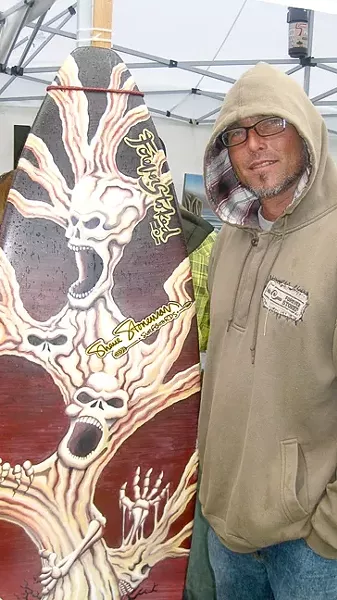 HAUNTED SURFBOARD : Thanks to the weather, Chris Pedersen of Forever Stoked sold a number of hats at the Nas and Damian Marley concert. - PHOTO BY NICK POWELL
