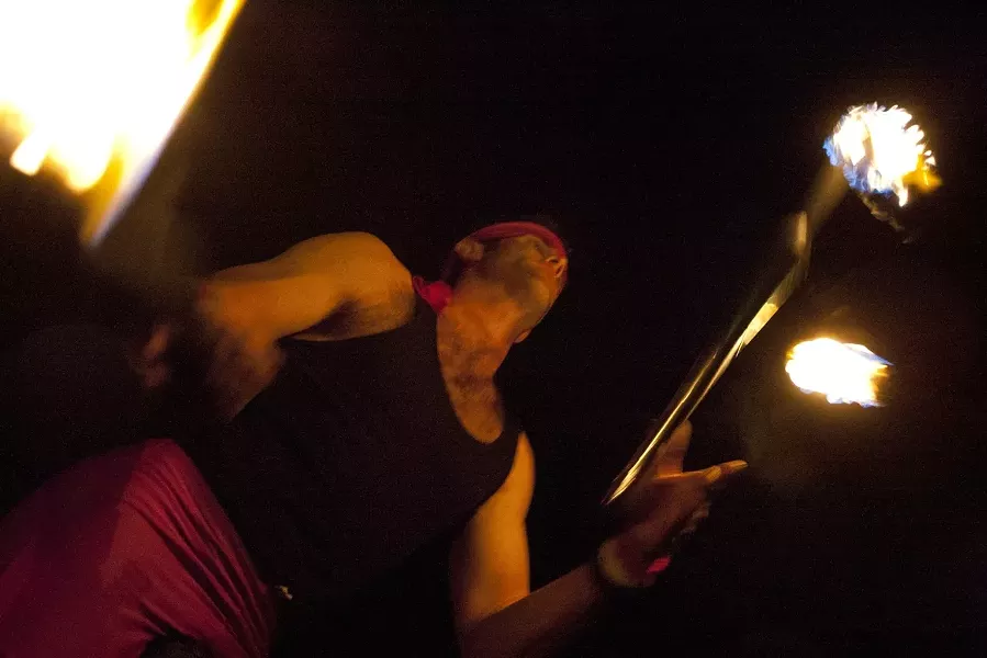 ON FIRE! : A unicycling fire juggler entertains the damp crowd at Box City, a New Times art event on Miguelito Court that employed five Meathead Movers trucks, each with a different theme. - PHOTO BY STEVE E. MILLER