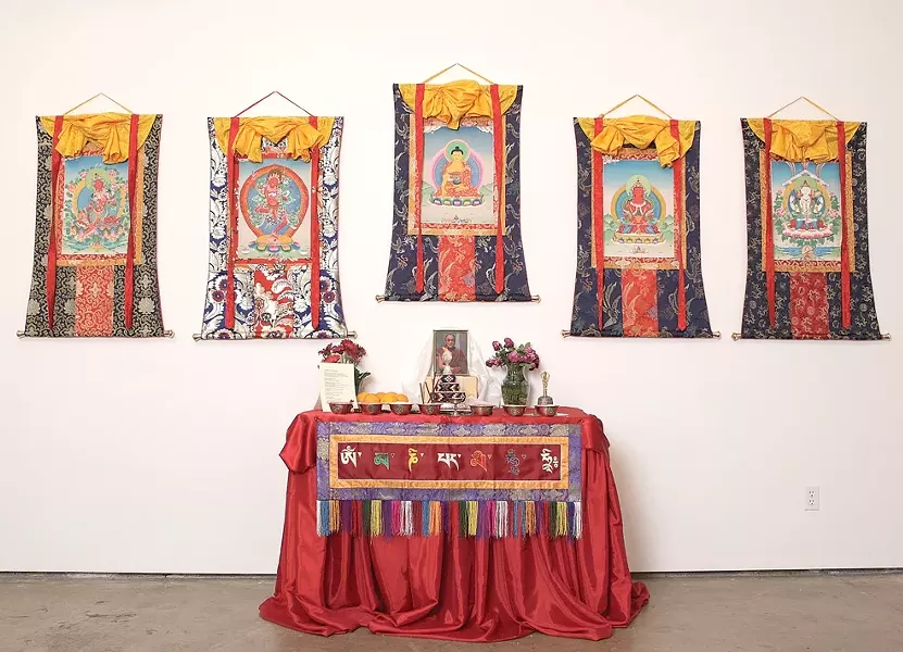DEITIES BY THE HANDFUL : Five thankas from the exhibit, depicting five different Buddhas or deities, are mounted on silk brocade backgrounds. The center column beneath the image represents a door through which people can enter the thanka. - PHOTO BY STEVE E. MILLER