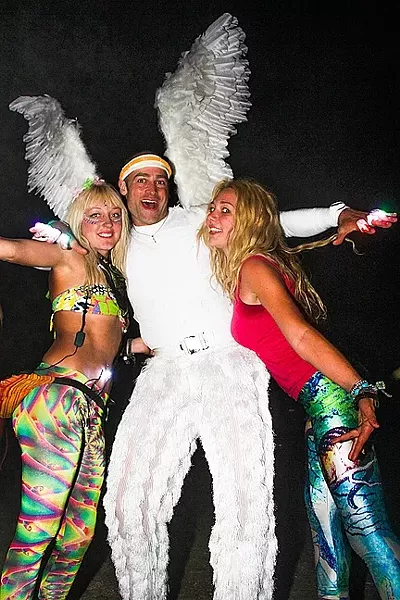 FESTIVAL FASHION: Festival fan Samy Boogaard (left) meets and embraces a man dressed as an angel, along with another happy-go-lucky young lady on the dance floor in 2014. - PHOTO BY DYLAN HONEA-BAUMANN