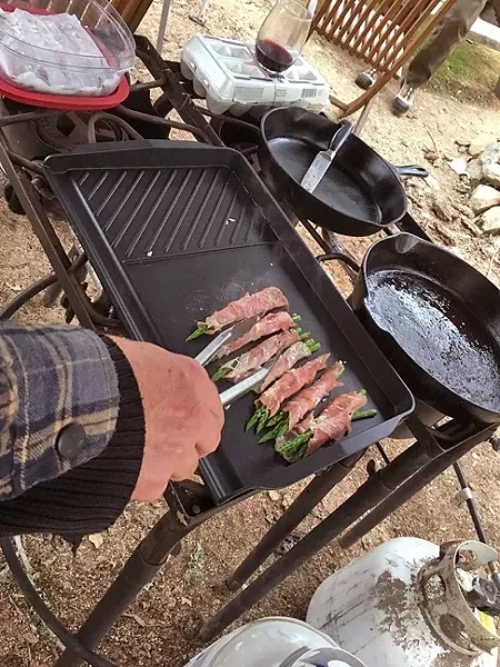 GRUB: What’s a men’s campout without decadent foods like these grilled prosciutto-wrapped asparagus with Asiago cheese appetizers? We also ate sausage, bacon, chorizo, and venison. - PHOTO BY GLEN STARKEY