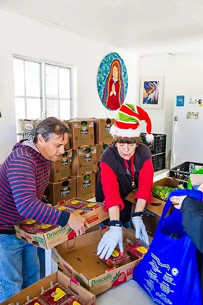 A HELPING HAND: Jorge Manly-Gil (left) and Karen Claydon (right) distribute food to the needy at the Catholic Worker in Guadalupe. - PHOTO BY JAYSON MELLOM