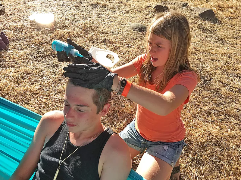 TO DYE FOR Sixteen-year-old Ezra Dickey finds a willing lady friend to apply electric blue hair dye, which he was gifted from an older Live Oak attendee with a blue beard. - PHOTO BY GLEN STARKEY