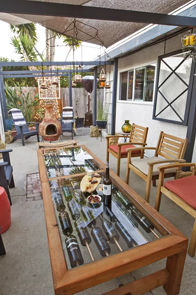 WINE LOVERS' DELIGHT Karen and Mark Libby's Shell Beach rental features a temporary arbor festooned with sun sails set in concrete-filled buckets and a custom wine table Mark created under WeevilWorks, the name of his woodworking business. - PHOTO BY JAYSON MELLOM