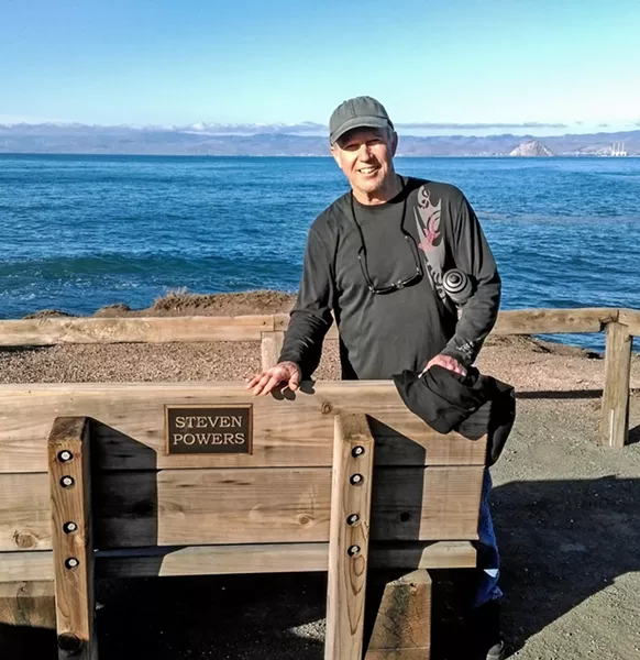 GOT THE POWER(S) Steve Powers, who has worked as an arts promoters for more than 40 years, stands by a bench named for a different Steve Powers at Montana de Oro. - PHOTO COURTESY OF STEVE POWERS