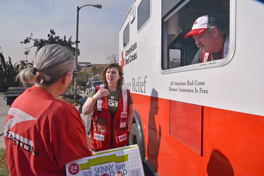 RED CROSS RESPONSE Red Cross Response Vehicles become focal points in disaster-stricken neighborhoods where neighbors regroup, collect water or snacks, and receive breathing masks. - PHOTO BY DERMOT TATLOW COURTESY OF THE RED CROSS