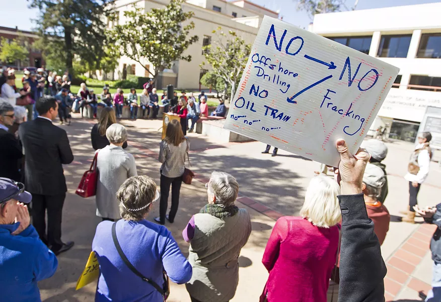 SIGN OF THE TIMES An activist holds up a sing at a recent anti-oil drilling press conference detailing what he believes to be the current fight in SLO County: the Phillips 66 rail spur, a petition to ban fracking, and resistance to offshore oil drilling. - PHOTO BY JAYSON MELLOM