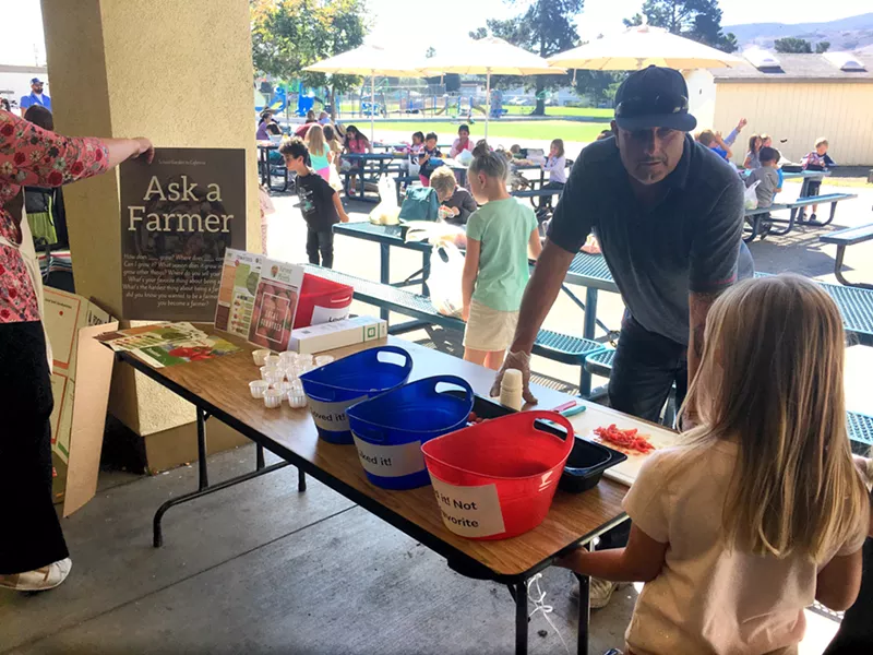 FRESH AND LOCAL Javier Magana, the farmer at Red Barn Farm, talks to students of C.L. Smith Elementary School about the benefits and tastiness of his locally grown tomatoes. - PHOTO BY KAREN GARCIA