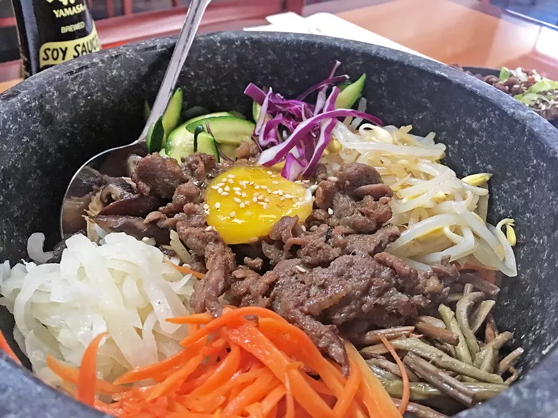 THAT SAUCE THOUGH Asian Bistro's Hot Stone Bibimbap sizzles for several minutes after it gets to the table. It comes with delicious house-fermented, spicy-sweet sauce to drizzle all over the bowl as you mix that egg yolk in with rice, beef, and fresh veggies. - PHOTO BY CAMILLIA LANHAM