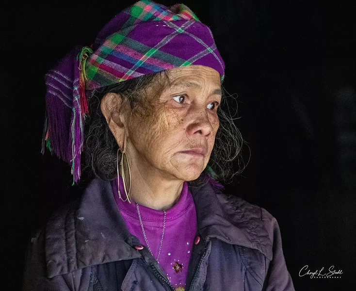 A WOMAN WITH A STORY Cheryl Strahl's Thoughtful in Hau Thao is a portrait featuring a dark, monochromatic background. The woman seen in the picture was caring for both her daughter and her grandson at the time the photo was taken. - PHOTO COURTESY OF CHERYL STRAHL