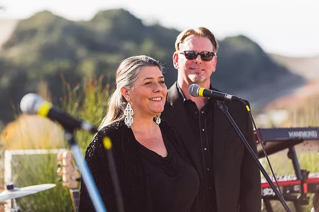 THE MAN (AND WOMAN) IN BLACK: Central Coast LIVE! founders Jennifer and Brad Golden welcome local musicians and dedicated fans during the Dec. 5 launch party for their company’s new livestream music radio app, which features exclusively local musicians. - PHOTO COURTESY OF JP SAWYER OF JOHN PATRICK IMAGES