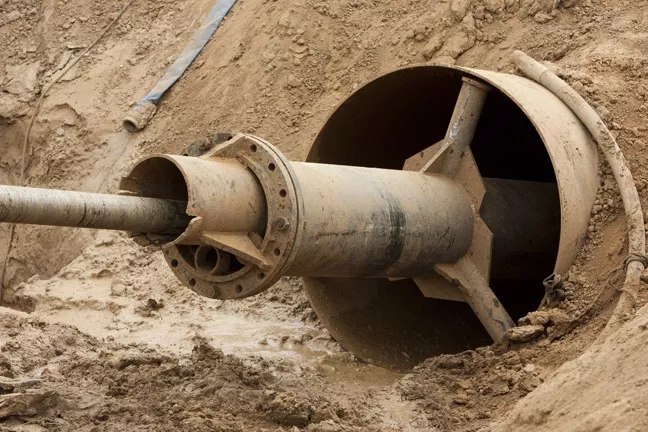 MIND THE GAP: The contractors put a 54-inch steal casing at the mouth of the hole to stabilize it. Sand from the Oceano-Nipomo Dunes caused the tunnel to cave in at least once, but the hard clay and stone of the upper Paso Robles Formation made sure it stood strong. - PHOTO BY STEVE E. MILLER