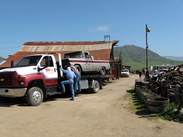 OFF THE FARM : Tow company workers endeavor to haul away one of 26 vehicles county code officials had a warrant to remove from Dan DeVaul’s Sunny Acres ranch. In the end, only six were removed. - PHOTO BY PATRICK HOWE